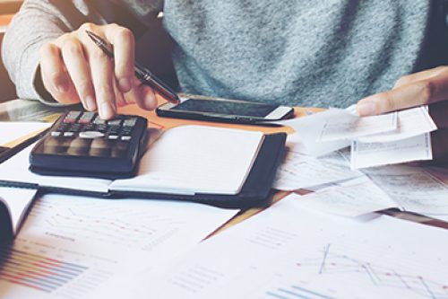 Man using calculator and calculate bills in home office.